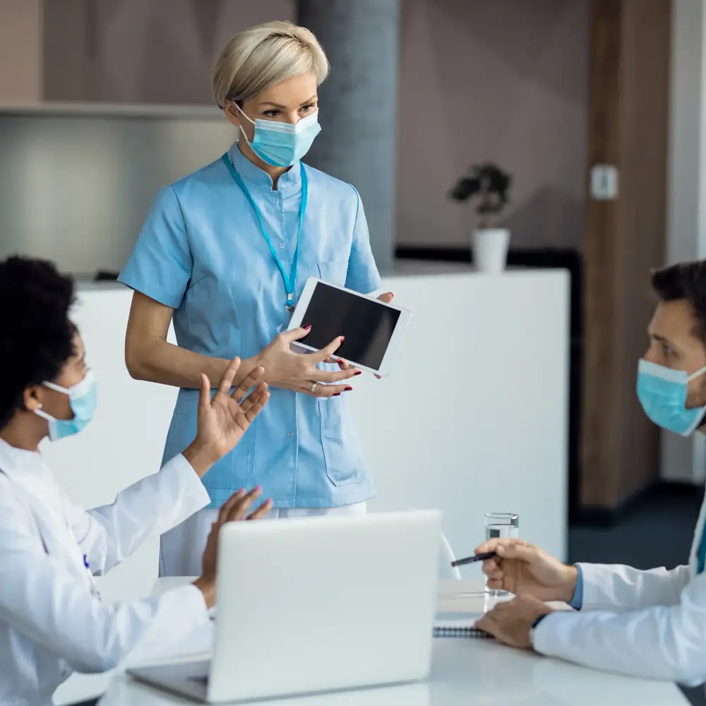 Healthcare workers collaborating on a tablet in a clinic